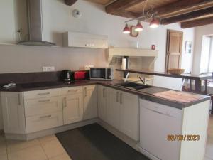 a kitchen with white cabinets and a black counter top at L'ammonite in Chaunay
