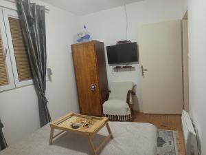 a living room with a tv and a chair and a table at GUESTHOUSE TARA in Kolašin