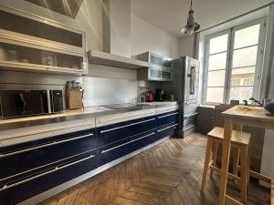 a kitchen with stainless steel appliances and blue cabinets at Herem Charme de l ancien en centre ville in Clermont-Ferrand +16 photos