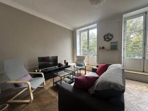 a living room with a couch and chairs and a tv at Herem Charme de l ancien en centre ville in Clermont-Ferrand