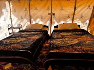 two beds in a room with a tent at Maha Kutch Rann Camp in Dhordo