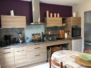 a kitchen with wooden cabinets and a table at Le gîte de la butte in Champagné-Saint-Hilaire