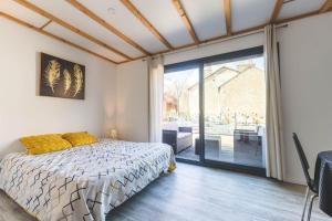 a bedroom with a bed and a large sliding glass door at Le gite du marronnier in Montamisé