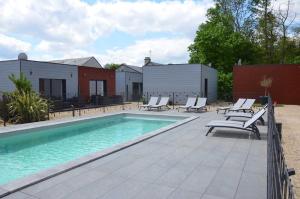 a swimming pool with lounge chairs next to a house at Le gite de l'erable in Montamisé