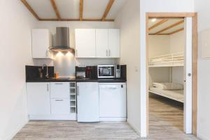 a kitchen with white cabinets and a bunk bed at Le gite de l'erable in Montamisé