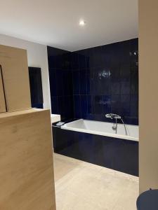 a bathroom with a white tub and blue tiles at Le troglo du château in Beaumont +7 photos