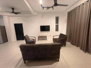 a living room with a couch and chairs and a tv at SWee Garden Homestay in Kota Tinggi