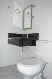 uma casa de banho com um WC branco e um espelho. em Brisa Do Vale Pousada em Itaobim