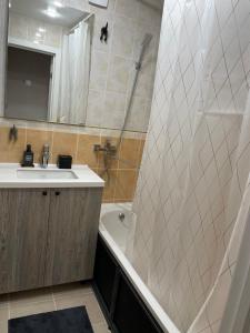 Un baño con lavabo, bañera y ducha. en Уютный апартамент, en Öskemen