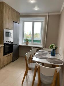 Una cocina con una mesa con sillas y un refrigerador. en Уютный апартамент, en Öskemen