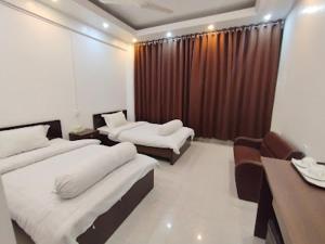 Lakshmanpur BālāpāraHotel Air-Star的一间酒店房间，里面有两张床、一张桌子和几把椅子。