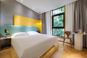 a bedroom with a large white bed and a window at Qiyu Hotel - Xian Bell Tower in Xi'an