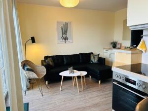 a living room with a black couch and a table at Sonnenstern - Sonnenverwöhnte Familienwohnung mit Balkon in Wangerooge