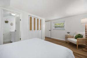 a white bedroom with a bed and a chair at Heights Haus in Peoria Heights
