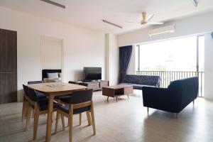Una sala de estar con una mesa y sillas y un sofá. en Cozy Seaview Escape 2BR 6pax bythesea bathroom, en Pulau Pinang