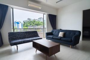 Una sala de estar con un sofá azul y una mesa de café. en Cozy Seaview Escape 2BR 6pax bythesea bathroom, en Pulau Pinang