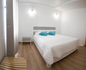 ein Schlafzimmer mit einem weißen Bett mit blauen Kissen in der Unterkunft PIX Apartments in Madalena