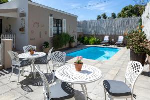 a patio with tables and chairs and a pool at The Potting Shed Guest House in Hermanus