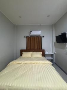 a bed in a small room with a television at Ban Mae Ku 