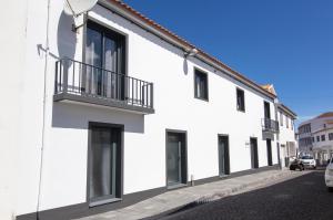 a white building with a balcony on a street at PIX Apartments in Madalena