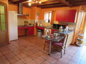 a kitchen with red cabinets and a table and chairs at Le moulin de chaume in Champagné-Saint-Hilaire