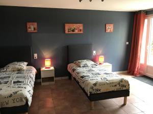 two beds in a room with two lamps on tables at Le moulin de chaume in Champagné-Saint-Hilaire