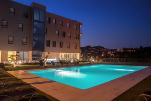 a swimming pool in front of a building at night at Lam Hotel Celorico de Basto in Celorico de Basto
