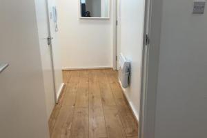 een hal met een deur en een houten vloer bij London 1 Bed Apartment close to Barking Station in Barking