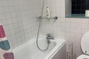 een badkuip met douchekop naast een toilet bij London 1 Bed Apartment close to Barking Station in Barking