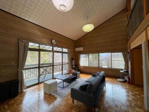 a living room with a couch and chairs and windows at Forest villa lake yamanaka in Wada