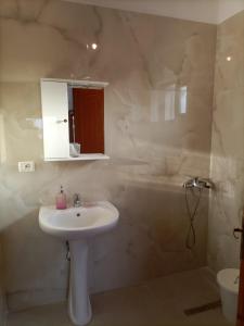 a white bathroom with a sink and a shower at Baci Apartments in Ksamil