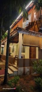 a house with a palm tree in front of it at Leela Grove Cottages Gokarna in Gokarna +26 photos