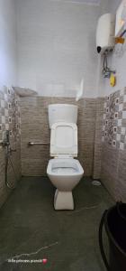 a bathroom with a white toilet in a stall at Leela Grove Cottages Gokarna in Gokarna