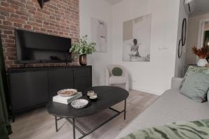 a living room with a coffee table and a brick wall at Harbor Apartments - Aparthotel przy Rynku in Katowice