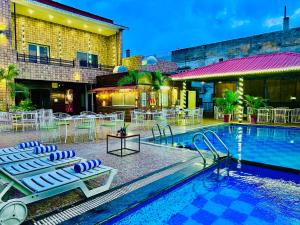 a pool with lounge chairs and a table and a building at Hotel Grand Bhagwat Udaipur Inn City Centre in Udaipur