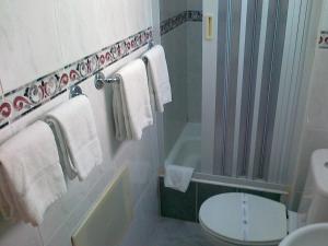a bathroom with a toilet and a tub and a sink at Real Caparica Hotel in Costa da Caparica