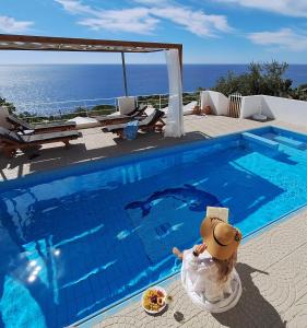 una persona sentada junto a una piscina en Silver Moon Villa, en Achlia
