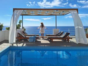 a woman in a white dress standing next to a swimming pool at Silver Moon Villa in Achlia