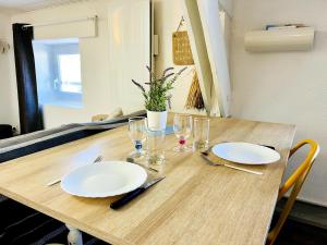 a wooden table with white plates and glasses on it at Le Petit Réaumur - Coeur de ville in La Rochelle +1 photo