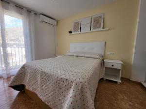 a bedroom with a bed with a white bedspread and a window at Apartamento in Carboneras