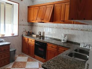 una cocina con armarios de madera y estufa negra en Casa Algarabía, en Sanlúcar de Barrameda