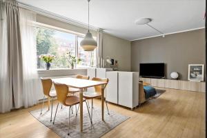 a living room with a table and chairs and a television at Charming studio apartment in the heart of Nørrebro, Copenhagen in Copenhagen