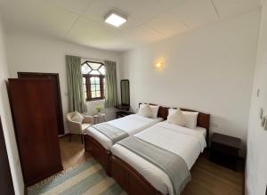 een slaapkamer met twee bedden en een raam bij Kings Villa Nuwara Eliya in Nuwara Eliya