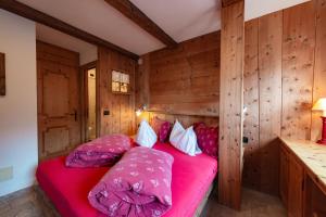 a bedroom with a red bed with wooden walls at Chalet Pian in Campitello di Fassa
