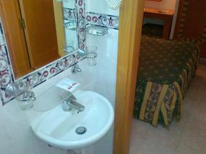 a bathroom with a white sink and a mirror at Real Caparica Hotel in Costa da Caparica