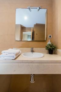 W łazience znajduje się umywalka i lustro. w obiekcie Villa de Madrid 17 w mieście Huelva +44 zdjęcia