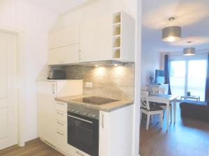 a kitchen with white cabinets and a dining room with a table at FeWo "Hafenquartier" in Barth