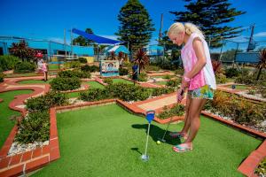 BIG4 Port Fairy Holiday Park في بور فيري: امرأة تلعب الغولف في حديقة