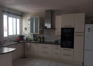 a kitchen with white cabinets and a black appliance at Maison de village in Île dʼAix