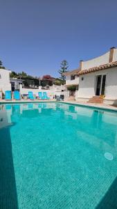 a large blue swimming pool with blue chairs in it at El Camarote in Mijas